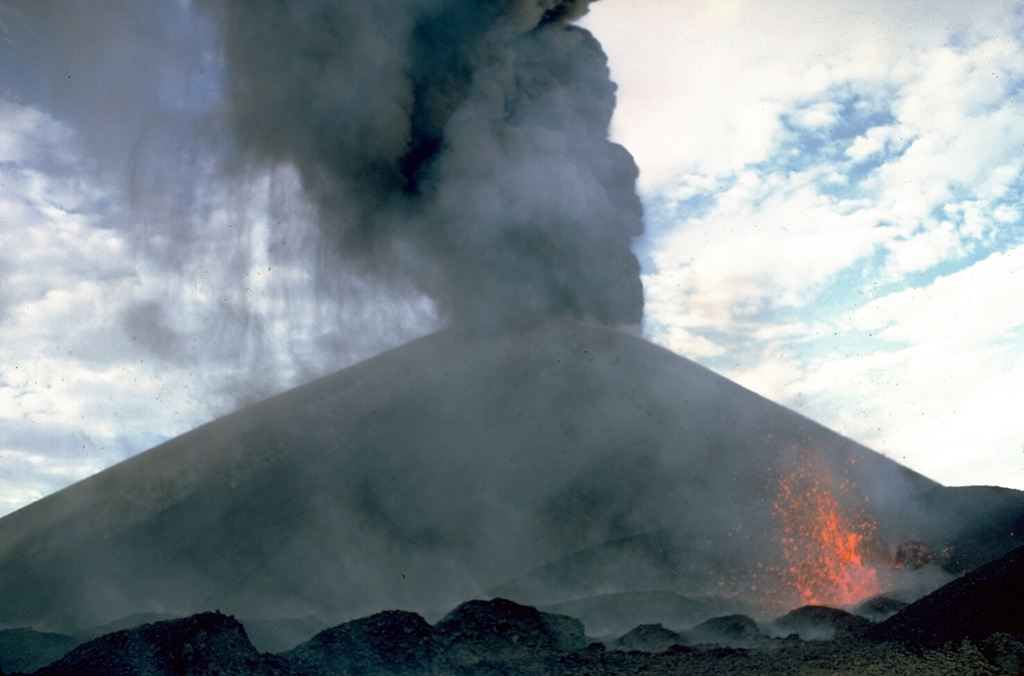 Ash falls at the left from a strombolian eruption column emanating from the summit crater of Cerro Negro volcano in 1968.  At the same time incandescent spatter (lower right) is ejected from a small vent on the south flank of the cone.  The 1968 eruption began on October 23 and lasted until December 15.  The south-flank vent also fed a lava flow that traveled 1.5 km. Photo by William Melson, 1968 (Smithsonian Institution).