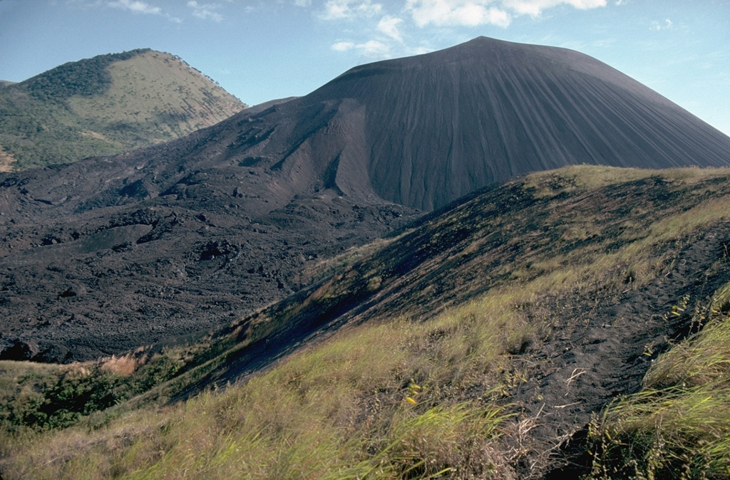 Cerro Negro, the largest and youngest of a group of four cinder cones that were constructed along a N-S line, is Central America's youngest volcano.  Since its formation in 1850, Cerro Negro has produced frequent explosive eruptions, building a 250-m-high cinder cone surrounded by a fresh lava field.  This 1995 photo from the southernmost of the older cones to the NNE shows flow levees and lava flows at the left side of Cerro Negro that were produced during the 1995 eruption.  The vegetated peak in the background is part of the Las Pilas complex. Photo by Britt Hill, 1995 (Southwest Research Institute).