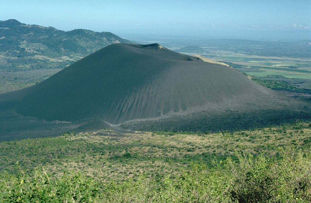 Cerro Negro volcano is viewed here on December 6, 1995, from the SE on the flanks of Las Pilas volcano.  The photo was taken on the final day of an eruption that began on May 28 or 29.  Minor ash eruptions had continued intermittently until August 16 and resumed November 19 until December 6.  The eruption was accompanied by growth of a small lava dome in the summit crater and lava flows that traveled down the north flank Photo by Britt Hill, 1995 (Southwest Research Institute).