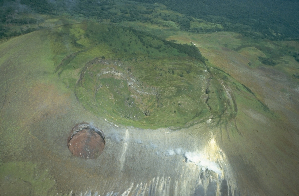 The summit crater of Las Pilas volcano is 700 m wide and 120 m deep.  Concentric fissures illustrate its collapse origin.  Steam rises from fumaroles along a transverse fissure that extends from the lower right to the upslope (northern) side of the dramatic El Hoyo pit crater at the lower left.  Photo by Jaime Incer 1981.