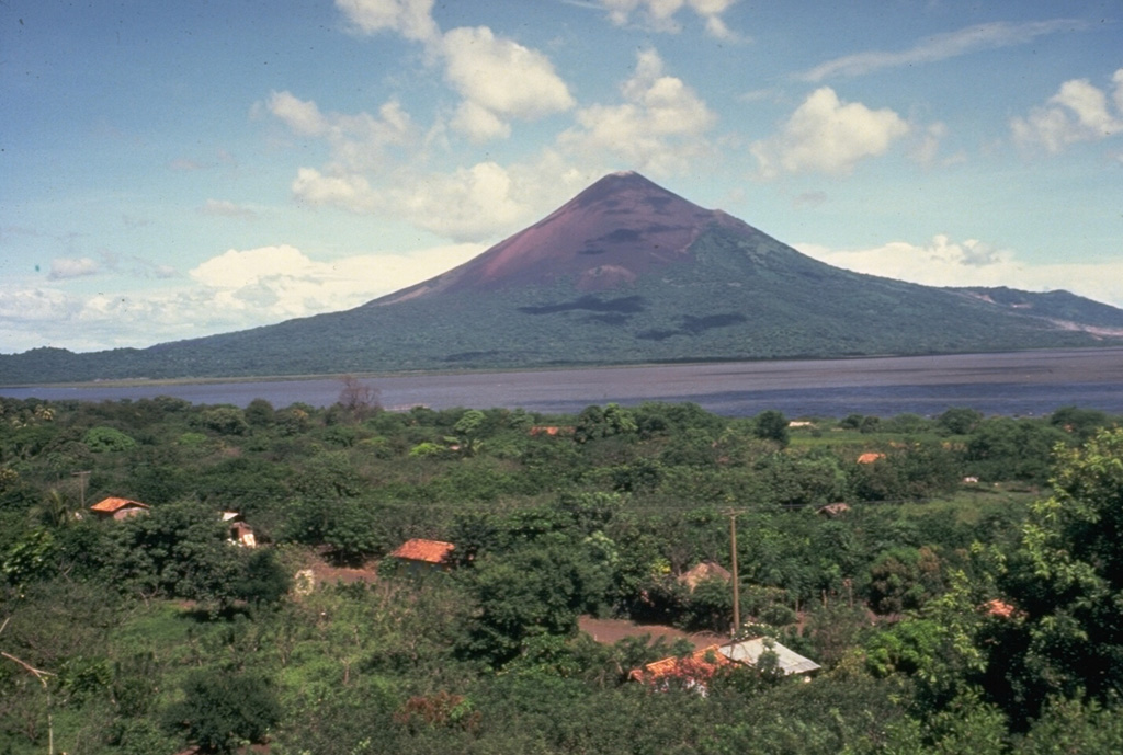 Momotombo is a young, 1297-m-high stratovolcano that rises prominently above the NW shore of Lake Managua, forming one of Nicaragua's most familiar landmarks.  Seen here from the SW,  Momotombo began growing about 4500 years ago and consists of a somma from an older edifice that is surmounted by a younger cone with a 150 x 250 m crater.  Young lava flows from Momotombo have flowed down the NW flank into an unnamed, 4-km-wide caldera.  Momotombo has a long record of strombolian eruptions, with occasional larger explosive activity. Photo by Jaime Incer.