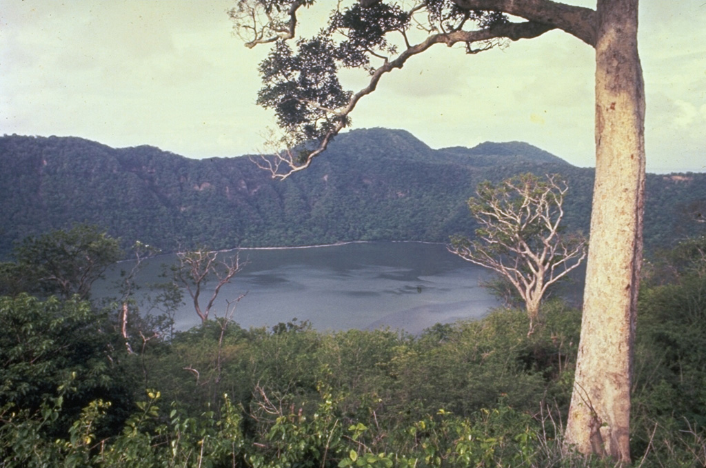 The summit caldera of Apoyeque volcano is filled by a scenic lake.  The age of the latest eruption of Apoyeque is not known, but human footprints underlie pumice deposits thought to originate from Apoyeque volcano or a nearby vent beneath Lake Managua.  This view is from the west caldera rim with the Chiltepe Hills in the background.    Photo by Alain Creusset-Eon, 1970 (courtesy of Jaime Incer).