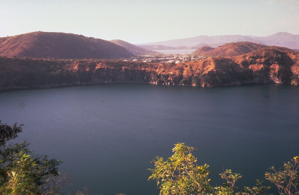 The steep-walled crater Laguna de Asososca provides water for the adjacent capital city of Managua.  The elongated 1.3 x 1 km wide lake lies north of Laguna de Nejapa along the Nejapa-Miraflores lineament and is viewed here from the SE.  In the background, beyond a bay of Lake Managua (the light-colored body of water at the upper right-center), is the Chiltepe Peninsula.  This Laguna de Asososca is not to be confused with another crater lake of the same name at the southern end of the N-S-trending Las Pilas volcanic complex. Photo by Jaime Incer.