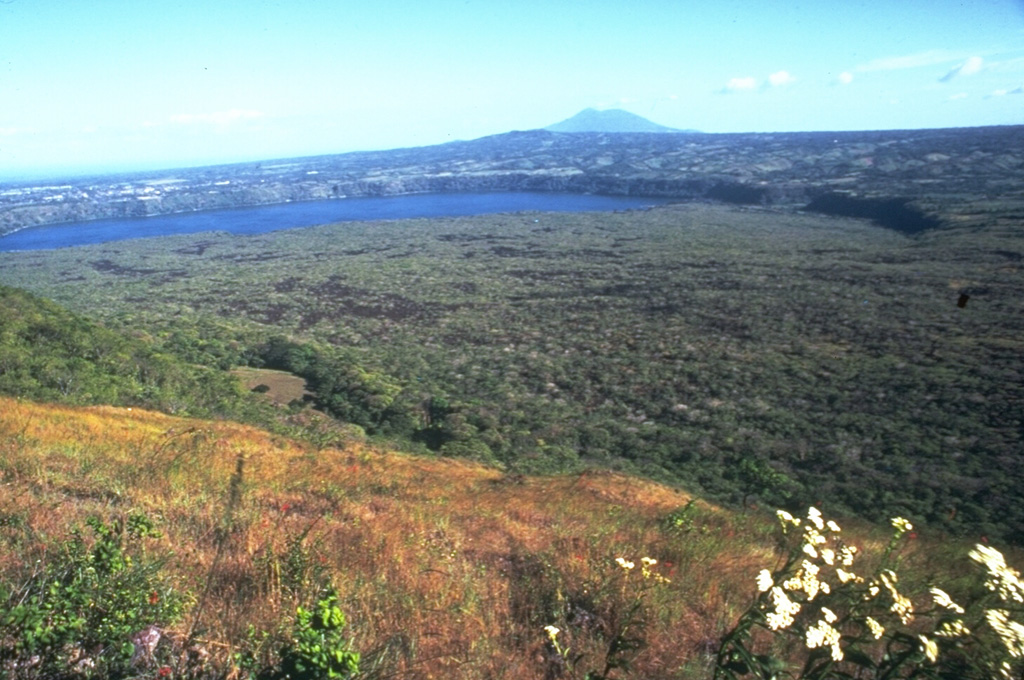 A broad expanse of lava flows extends across the floor of Nicaragua's Masaya caldera, with the wall forming the arcuate rim in the background. The lava flows originated from the post-caldera cones of Masaya and Nindirí. Lake Masaya is located against the eastern caldera wall. Recent lava flows have flooded much of the caldera and have overflowed its rim in one location on the NE side. This view from the NW shows Mombacho volcano in the distance. Photo by Jaime Incer.