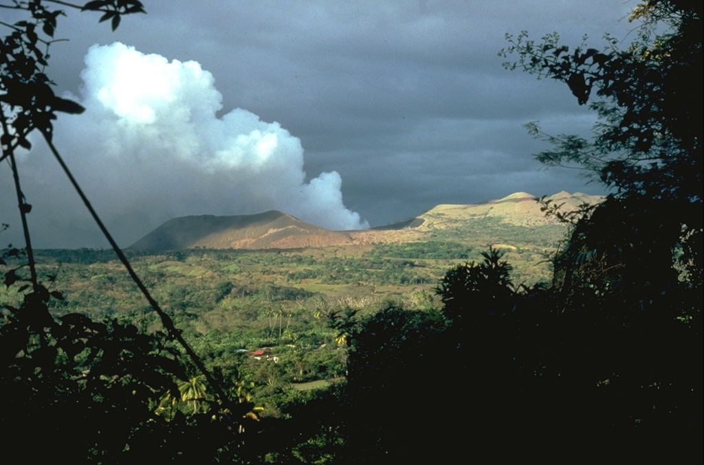 Masaya volcano is noted for long-duration periods of voluminous gas emission.  This February 1982 photo from the NE shows a gas plume pouring from Santiago crater, during the 4th gas emission crisis of the 20th century.  Emission of a very large gas plume had continued without interruption since the fall of 1979.  Remote sensing of SO2 revealed continued high level flux, with a 1500-2000 tons/day average during 1980.  Distribution of the gas plumes by prevailing winds caused widespread crop damage. Photo by Dick Stoiber, 1982 (Dartmouth College).