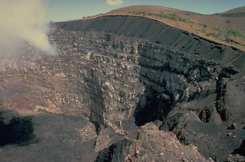 A thick stack of about 20 lava flows is exposed in the 230-m-high eastern walls of Santiago crater, overlain by a sequence of black basaltic ash deposits.  The 600-m-wide Santiago crater is seen here from a viewpoint on the SW crater rim.  Santiago crater is located on the west side of the post-caldera cone of Nindirí, and has been the source of most historical eruptions of Masaya. Copyrighted photo by Katia and Maurice Krafft, 1983.