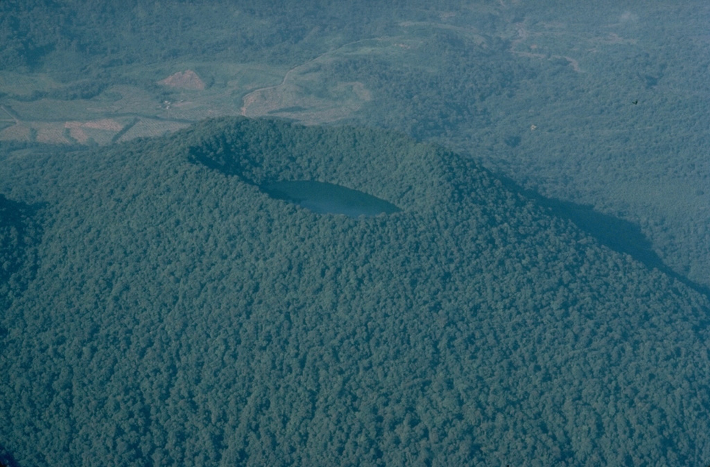 The last eruptions of Cerro Chato volcano, at the SE end of the Arenal volcanic complex, took place about 3500 years ago.  Phreatomagmatic explosions produced a crater at the summit of the volcano that is now filled by a lake.  This 1983 aerial view from the east shows the densely forested summit of Cerro Chato, with the higher western rim rising above the crater lake. Copyrighted photo by Katia and Maurice Krafft, 1983.