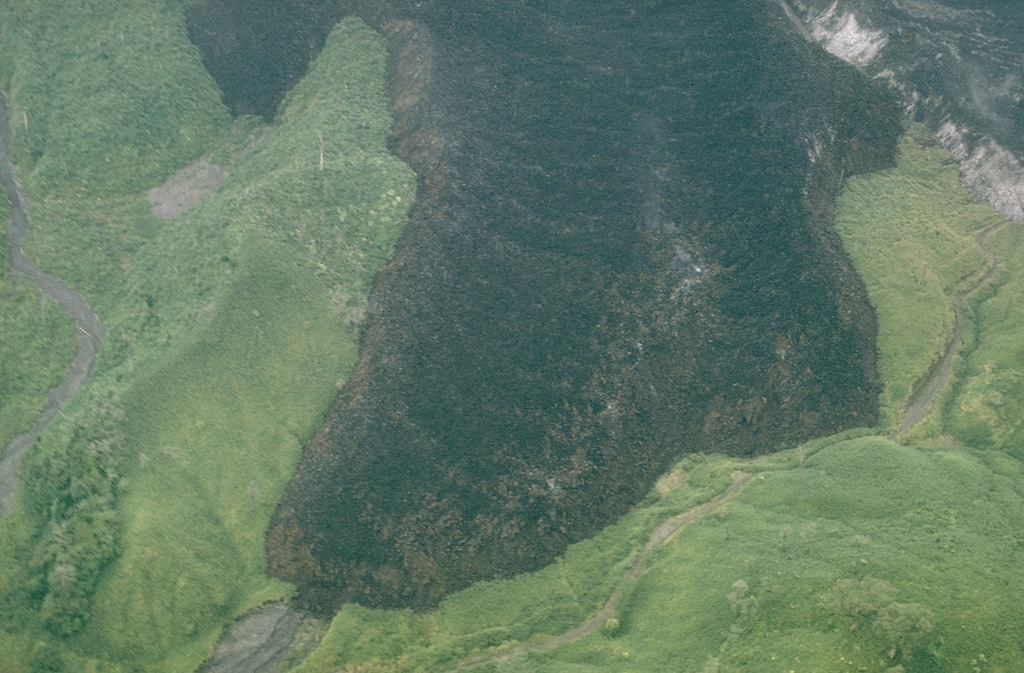 This view shows a lava flow on the WNW flank of Arenal, which originated from Crater A on the lower west flank. At the time of this September 1969 photo the flow had been active for one year. The thick andesite flow initially traveled down the Río Tabacón valley to the NW, but multiple lobes eventually filled different drainages. Photo by William Melson, 1969 (Smithsonian Institution).