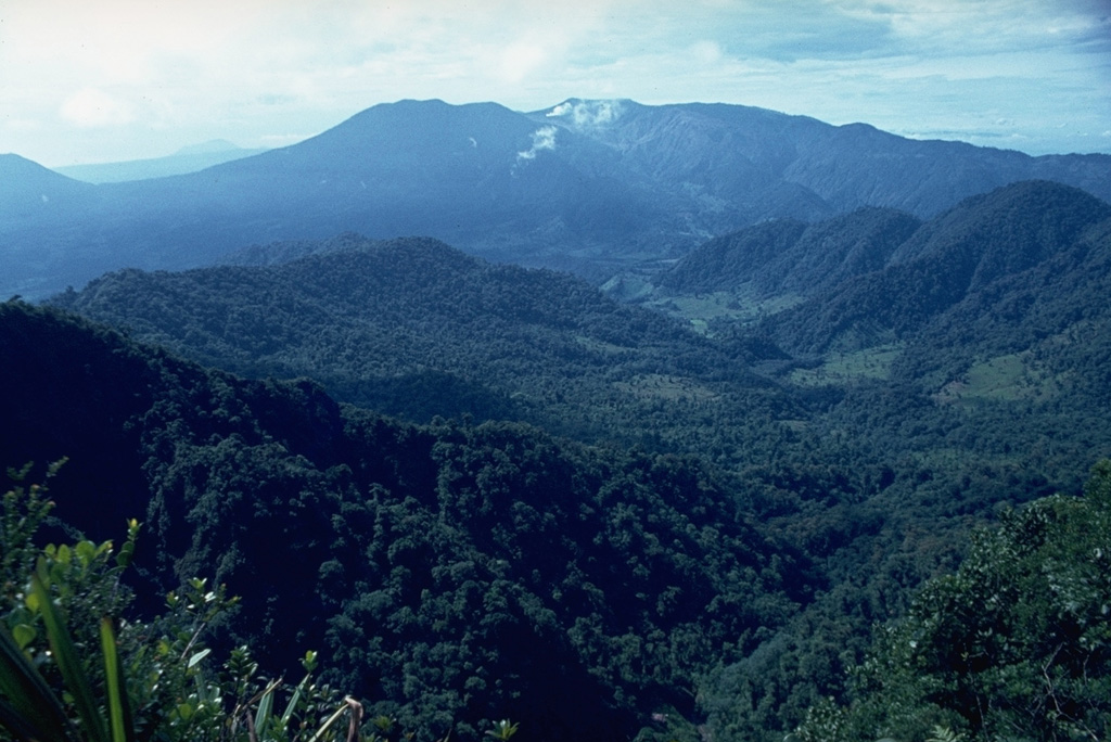 Poás volcano is visible in this view from the NW with small gas plumes rising from the Botos cone in the center of the complex; the peak to its left is von Frantzius cone. The flank of Cerro Congo is across a saddle from von Frantzius on the far-left horizon. Two large calderas are at the summit, the youngest of which formed about 40,000 years ago. Photo by Dick Berg, 1969 (courtesy of William Melson, Smithsonian Institution).