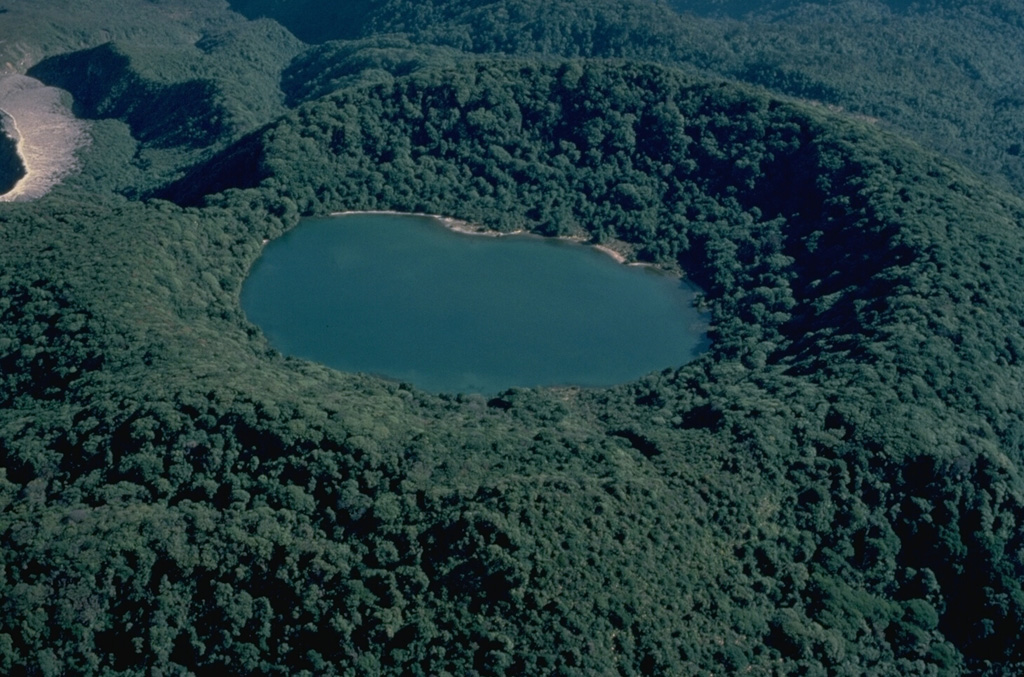 Densely forested Botos cone, the southernmost of the three volcanic cones forming the summit of Poás volcano, last erupted about 7500 years ago.  Following this eruption activity shifted north to the presently active crater, whose unvegetated rim is seen at the upper left.  The floor of the 1-km-wide Botos maar is now covered by the waters of Laguna del Agua Fria ("Cold Water Lake"). Copyrighted photo by Katia and Maurice Krafft, 1983.