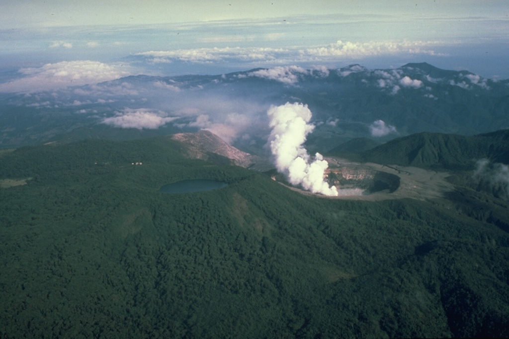 Poás is a broad volcano with a summit area containing three craters and is one of the most active volcanoes of Costa Rica. This photo from the east shows a plume rising from the active summit crater, which has been the site of frequent phreatic and phreatomagmatic eruptions since 1828, and the lake filled Botos crater to the left.  Photo by Mike Carr (Rutgers University).