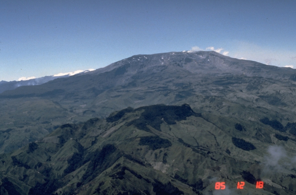 Nevado del Ruiz is a broad glacier-covered volcano that covers more than 200 km2. The modern cone consists of a cluster of lava domes constructed within the summit caldera of an older edifice. The ash-mantled summit is seen here from the ESE on 18 December 1985, a little more than a month after the catastrophic eruption of 13 November. The devastating 1985 lahars swept down four major river drainages that day and caused around 24,000 fatalities. Photo by Norm Banks, 1985 (U.S. Geological Survey).