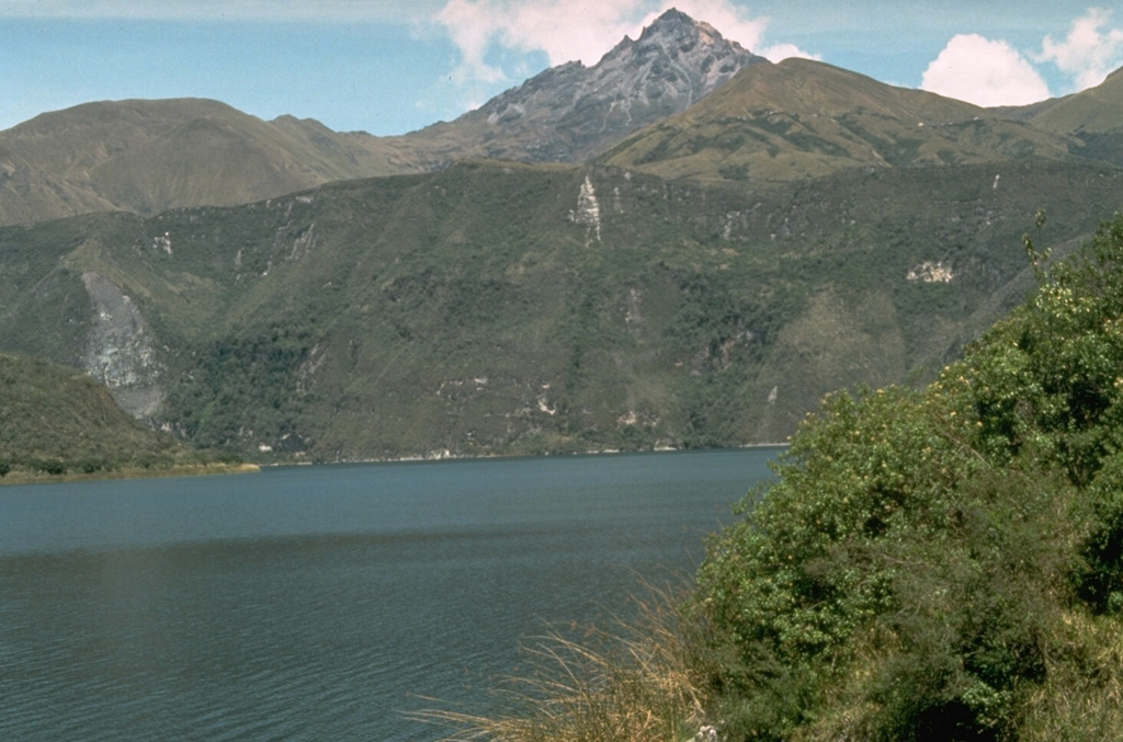 Sharp-peaked Cotacachi stratovolcano rises above the caldera lake of Cuicocha volcano.  The northern caldera wall truncates the flank of the heavily eroded Cotacachi.  The caldera was formed during powerful explosive eruptions about 3100 years ago that produced 4.8 cu km of pumice-rich pyroclastic flows and airfall tephra that blanket the surrounding countryside. Photo by Tom Pierson, 1992 (U.S. Geological Survey).