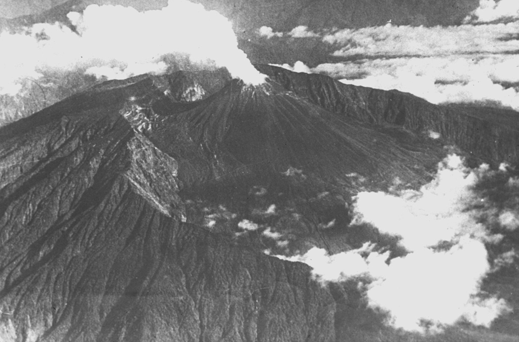 A steam plume, seen in a 1944 aerial view from the SE, rises above the summit crater of Reventador volcano.  An eruption during February 24 to March 1, 1944 caused ashfall in the Andes and produced a lava flow down the Río Ouijos.  The steaming El Reventador stratovolcano is nestled within the rim of an arcuate caldera that is breached widely to the east.  It rises 1300 m above the caldera floor and is one of Ecuador's most active volcanoes. Photo courtesy of Minard Hall (Escuela Politécnica Nacional, Quito), 1944.
