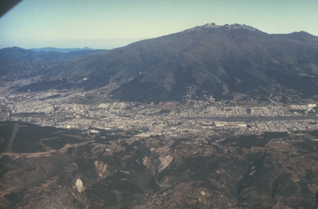 Guagua Pichincha stratovolcano rises immediately to the west of Ecuador's capital city, Quito.  A small lava dome is located at the head of a 6-km-wide breached caldera, which is out of view beyond the horizon in this photo.  The caldera formed during a late-Pleistocene slope failure about 50,000 years ago.  Many minor eruptions have occurred since the Spanish era; the volcano's largest historical eruption in 1660 deposited 30 cm of ash on Quito.    Photo by Minard Hall, 1982 (Escuela Politécnica Nacional, Quito).