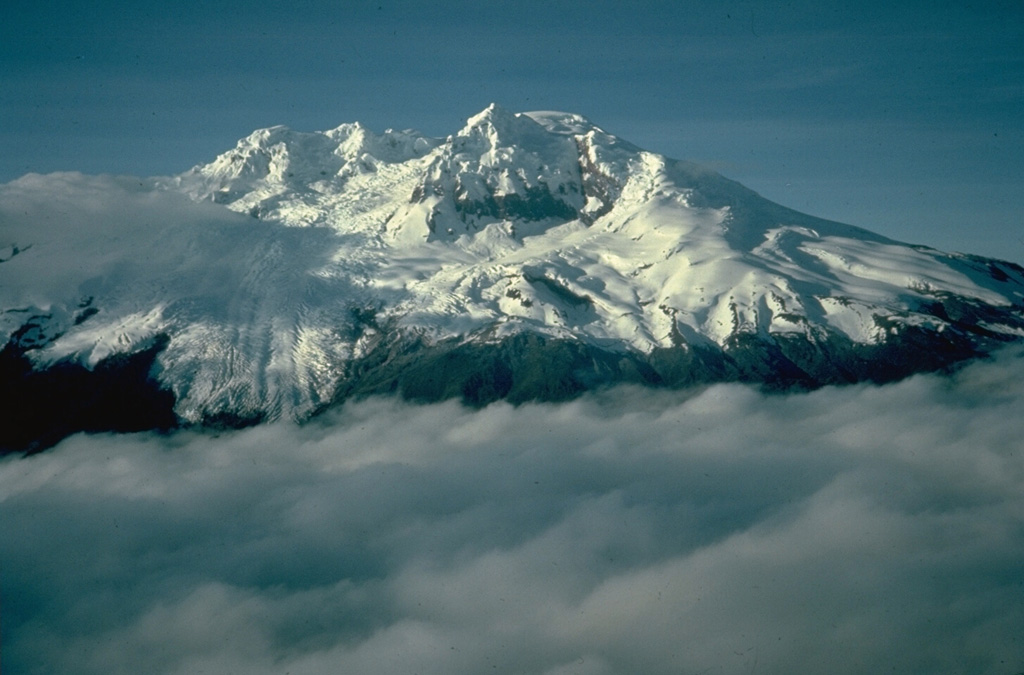 Antisana is a massive, glacier-covered stratovolcano NE of Cotopaxi.  The 1.4 x 1.8 km summit crater, seen here from the north, is breached to the SE.  Viscous, youthful block lava flows have issued from radial fissures on the flanks of 5753-m-high Antisana.  The only unequivocal historical eruption took place from 1801 to 1802.  Eighteenth-century eruptions occurred NW of Antisana within Chacana caldera, which lies beneath the cloud bank in the foreground. Photo by Minard Hall, 1975 (Escuela Politécnica Nacional, Quito).