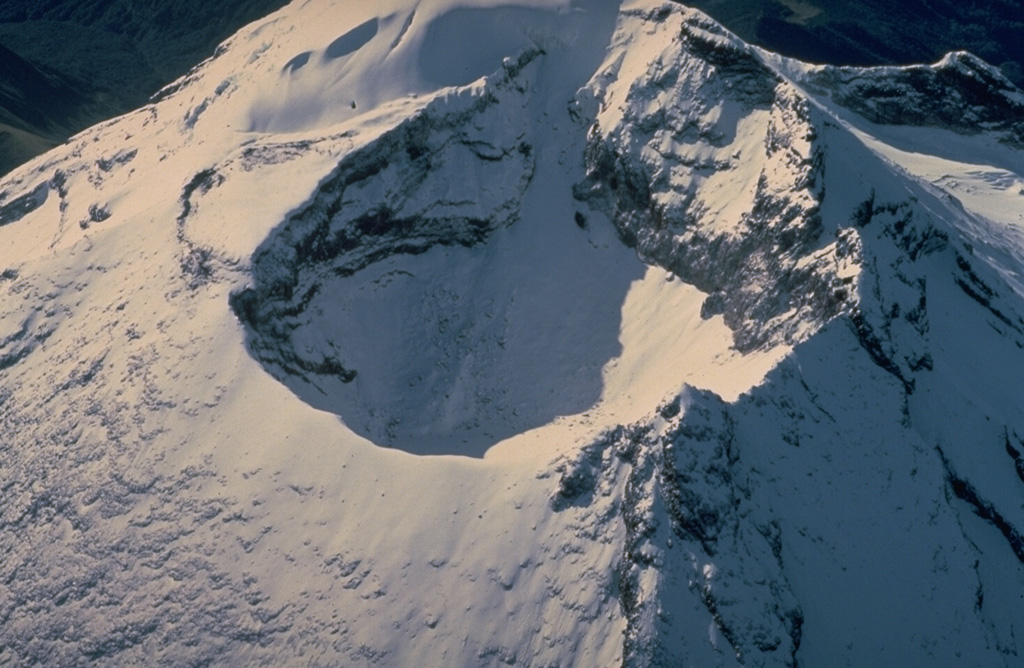 The morphology of the summit crater of Tungurahua volcano, seen from the the NNW in 1983, has frequently been modified by powerful explosive eruptions duinng historical time.  In 1873, the crater was 500-m wide and 80-m deep.  In 1923, near the end of an eruption that began in 1916, the crater assumed its present dimensions of 300 m in width and 200 m in depth.  The SE crater rim is 200 m higher than its NW rim. Copyrighted photo by Katia and Maurice Krafft, 1983.