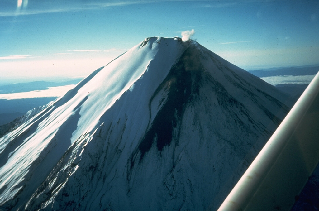 A dark lava flow descends the upper western flank of Sangay volcano in 1976.  The lava flow originated from the southernmost of several small craters at Sangay's summit.  This frequently cloud-covered volcano is Ecuador's most active.  Almost continuous minor explosive activity took place from 1728 until about 1916, and resumed in 1934.  Occasional larger eruptions produced detonations heard hundreds of km away.   Photo by Minard Hall, 1976 (Escuela Politécnica Nacional, Quito).