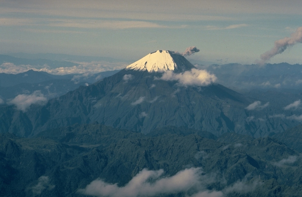 Sangay, Ecuador's most active volcano, towers above the tropical jungles east of the Andean crest.  Ash darkens the SW flank in this September 1983 view.  A small ash plume from the summit crater is deflected to the SW.  A plume from the previous explosion forms the dark inclined cloud at the extreme right.  More-or-less continual minor explosive eruptions have occurred from Sangay since 1934. Copyrighted photo by Katia and Maurice Krafft, 1983.