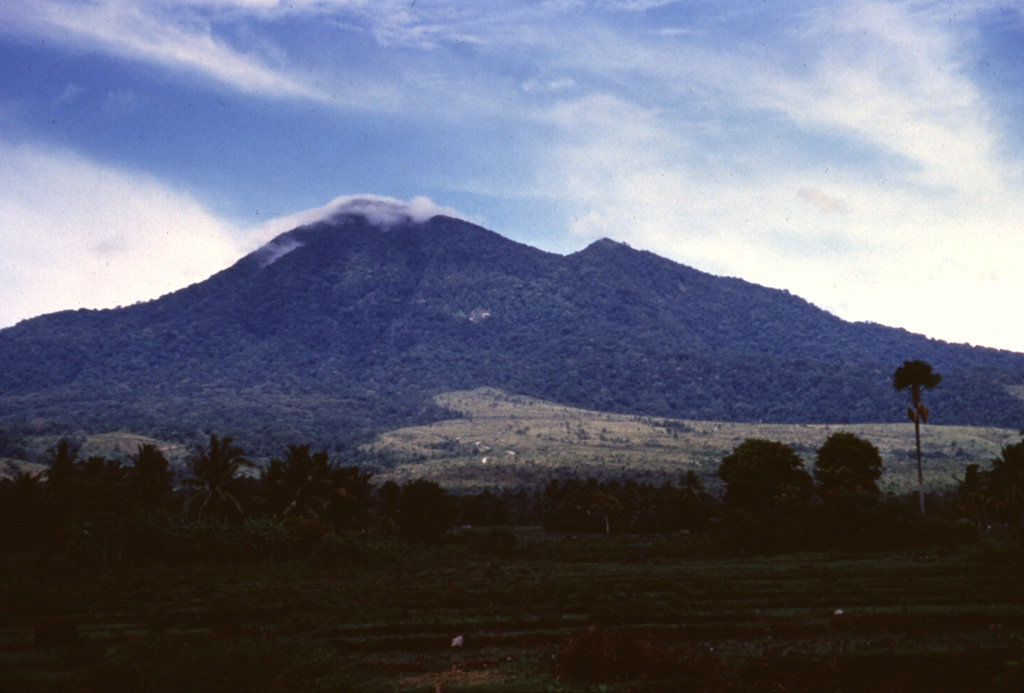 Gunung Seulawah Agam seen above farmlands on its eastern flank, is an extensively forested volcano of Pleistocene-Holocene age located in the province of Aceh at the NW tip of Sumatra. It was constructed within the large Pleistocene Lam Teuba caldera and a smaller nested 8 x 6 km caldera. Wispy clouds drape the summit, which contains a 400-m-wide crater. The van Heutsz crater on the NNE flank is one of several areas containing active fumarole fields. Anonymous, 1995.