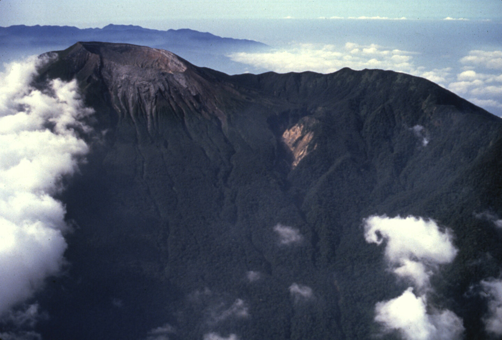 An aerial view from the N shows the summit crater of Dempo volcano to the upper left. The steep-walled crater contains a lake, which has been the source of frequent phreatic eruptions during historical time. Anonymous, 1991.