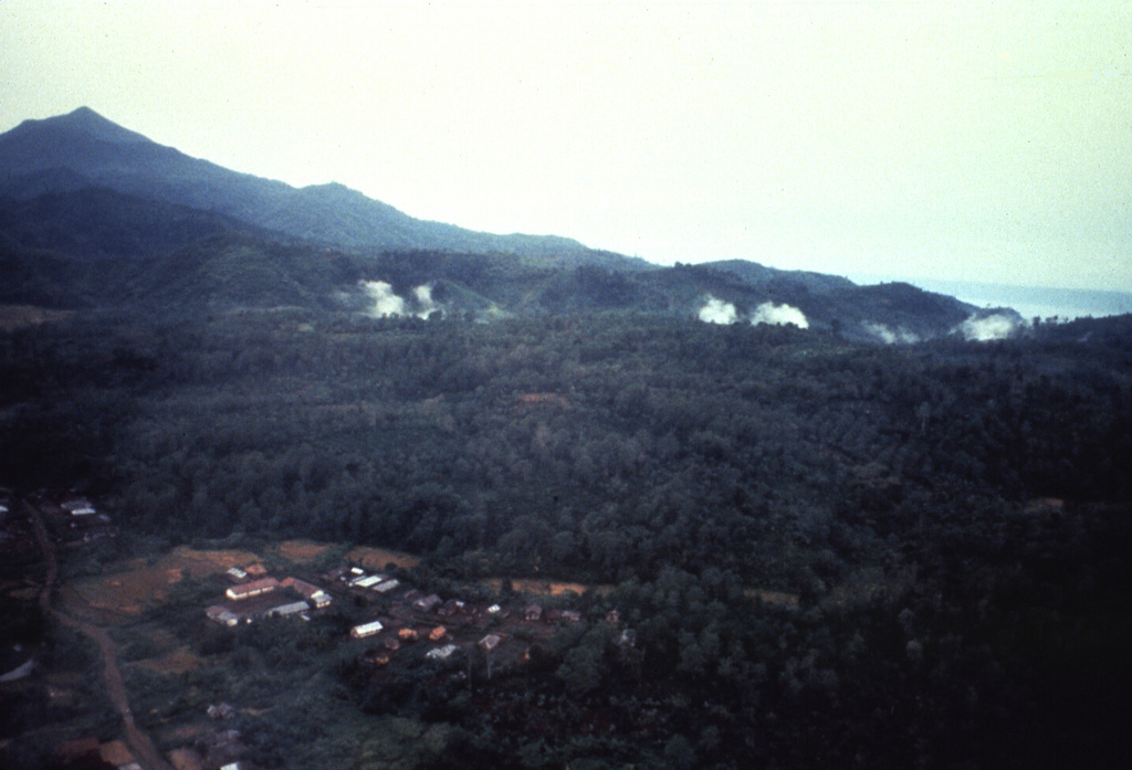 Plumes rise above a line of fumaroles at Hulubelu volcano in SE Sumatra. Gunung Tangganus rises at the upper left, east of the North Hulubelu fumarole fields that are aligned NE of, and parallel to, the Great Sumatran Fault. Hulubelu, also spelled Ulubelu, is an elliptical, 4-km-long caldera in SE Sumatra. The ages of the latest eruptions are not known, although geothermal activity, mud volcanoes, and hot springs occur at several locations. Anonymous, 1991.