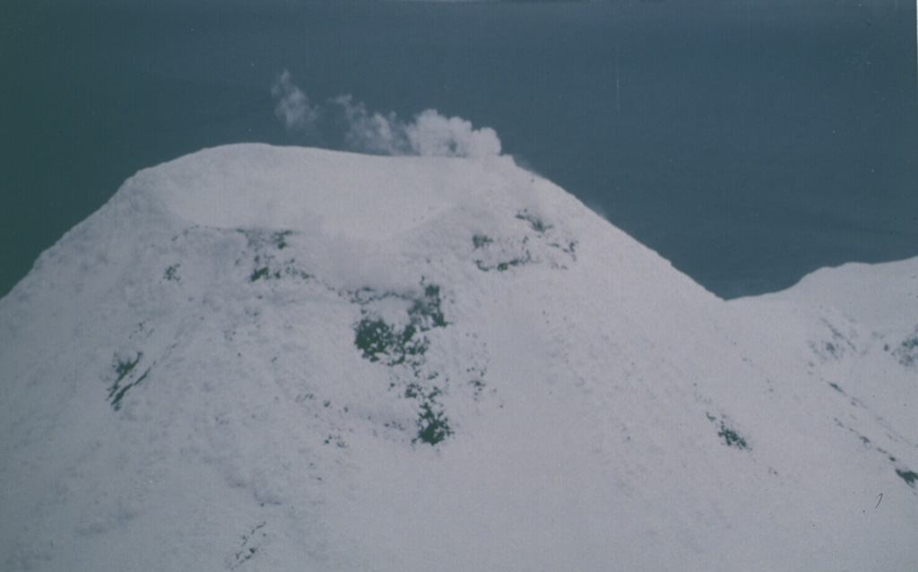This March 1987 view from the W shows typical emission from the summit crater of Kanaga.  Photo by Harold Wilson (Peninsula Airways), 1987 (courtesy of John Reeder, Alaska Div. Geology & Geophysical Surveys).
