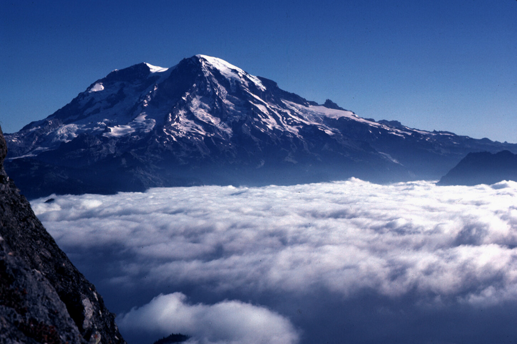 Mount Rainier is located east of the Puget Sound region, seen here from High Knob to the SW in 1981. Large Holocene mudflows from this heavily glaciated volcano have reached as far as the Puget Sound lowlands. Several postglacial tephras have erupted from Rainier, with tree-ring dating placing the last recognizable tephra deposit during the 19th century. Extensive hydrothermal alteration of the upper portion of the volcano has contributed to its structural weakness. Photo by Lee Siebert, 1981 (Smithsonian Institution).