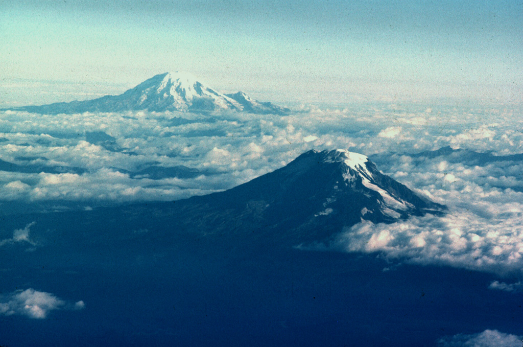 Mount Adams (lower right) and Mount Rainier are the two southernmost of a N-S-trending chain of large stratovolcanoes in the Cascade Range of Washington state. Adams Glacier can be seen descending to the SE from the summit icecap of Mount Adams in this aerial view from the south. The 1,250 km2 Mount Adams volcanic field contains numerous flank cones and lava flows, several of which erupted during the Holocene. Mount Rainier, Washington's highest peak, has been less active during the Holocene, but erupted during the 19th century. Photo by Lee Siebert, 1980 (Smithsonian Institution).