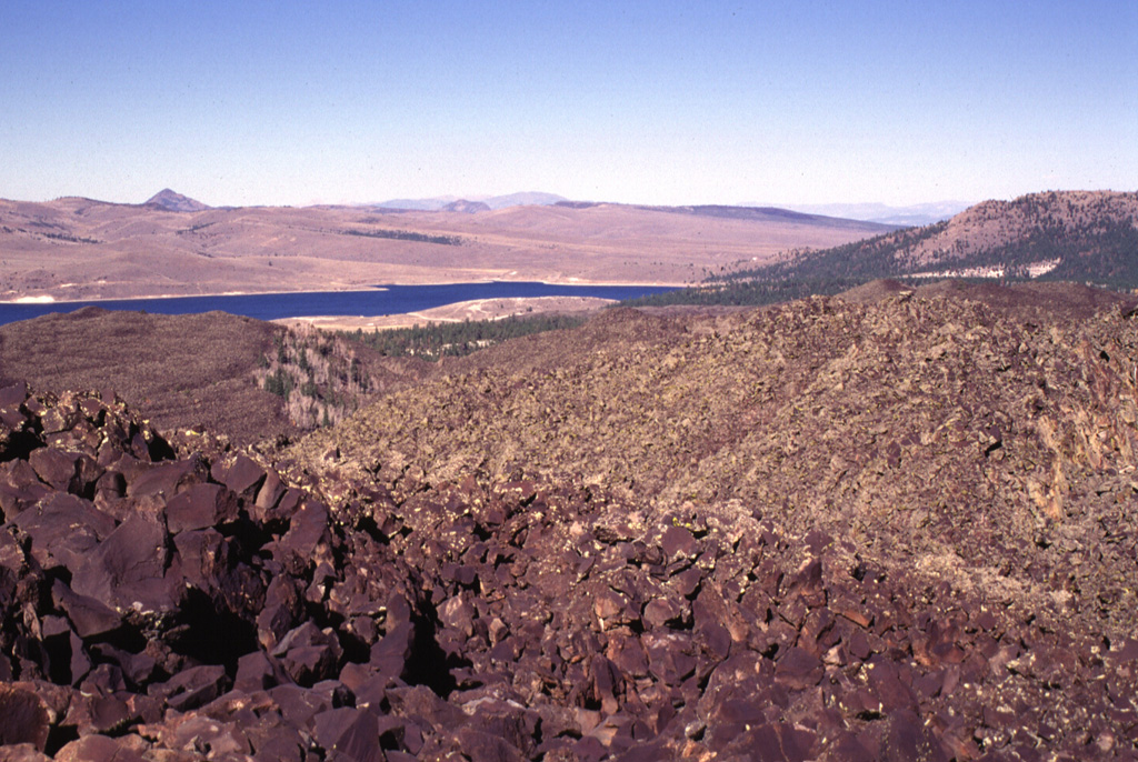 Blocky lava flows from near Miller Knoll reach nearly to Panguitch Lake in the distance to the NE.  Lava flows from the same vent traveled down Black Rock Valley to the SE.  This extensive lava field is one of the youngest of the Markagunt Plateau volcanic field. Photo by Lee Siebert, 1996 (Smithsonian Institution).
