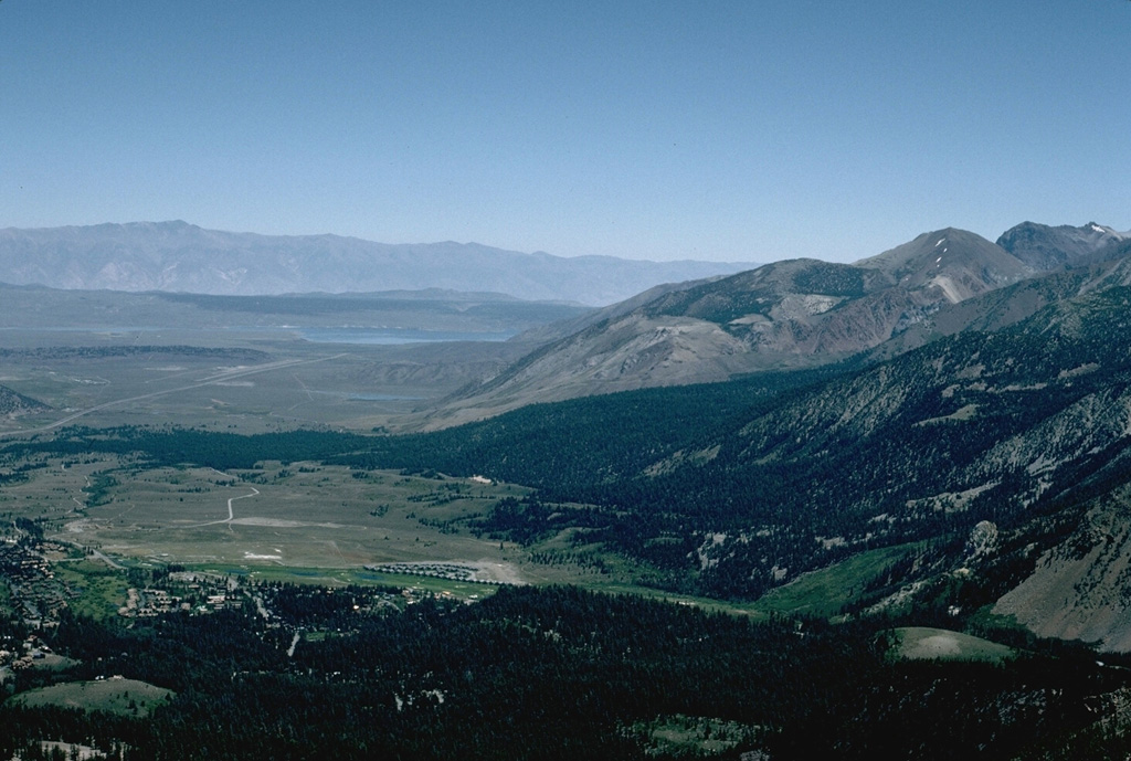 The south wall of the 17 x 32 km Long Valley caldera, seen from Mammoth Mountain on the SE topographic caldera rim, is composed of Paleozoic and Mesozoic metamorphic and igneous rocks.  Recent seismic swarms and soil gas anomalies have occurred on the flat caldera floor in the center of the photo. Photo by Victoria Avery, 1996 (Smithsonian Institution).