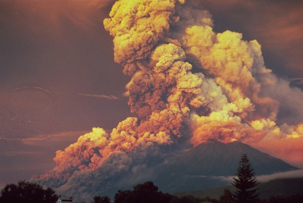 A powerful eruption at Fuego produced this ash plume at sunrise in October 1974. This view from Antigua Guatemala to the NE shows major pyroclastic flows moving down the eastern flank. Pyroclastic flows traveled 7 km but caused no fatalities. The 1974 eruption, the largest at Fuego since 1932, began with mild eruptions and small pyroclastic flows on 10 October. The eruption intensified on 14 October, with major Vulcanian eruptions occurring on that day, as well as 17-18, 19-20, and 23 October. Photo by William Buell, 1974.
