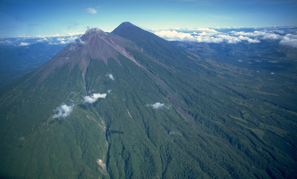 Fuego (left) and Acatenango are seen here from the SSE in 1994. The two edifices erupted from four major vents along a 5-km-long N-S trend, with the focus of volcanic activity progressively shifting to the south. The modern Fuego edifice is constructed within the collapse scar of the ancestral Mesata edifice, located between it and Acatenango. Copyrighted photo by Stephen O'Meara, 1994.
