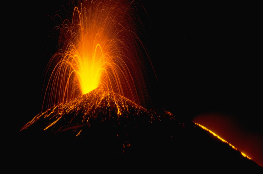 A Strombolian eruption at Pacaya volcano in Guatemala, November 1988. This time exposure shows the incandescent parabolic arcs of individual volcanic bombs explosively ejected from the vent. Larger bombs remain incandescent after they hit the surface of the cone and roll down its flanks. The orange line at the lower right is a lava flow extruding from a fissure on the upper NW flank of the MacKenney cone. Photo by Lee Siebert, 1988 (Smithsonian Institution).