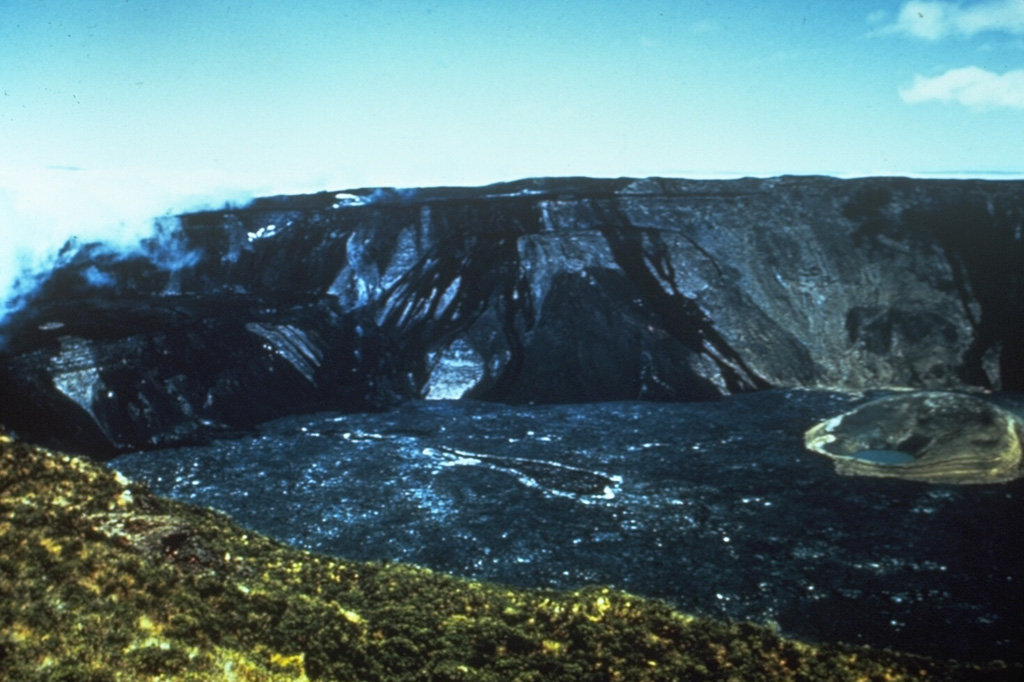 A 1966 photo from the NE caldera rim shows the effects of an eruption in 1958.  A major effusive eruption from vents on the SE, SW, and west caldera rims produced lava flows that descended the SE and SW flanks and also flowed into the caldera, completely covering the caldera floor.  One report suggested that the eruption was underway during a September-October 1958 visit; the eruption was in waning stages on a December 30, 1958 visit.  At this time, prior to additional collapse in 1968, the caldera was 800 m deep. Photo by Alan Root, 1966 (courtesy of Tom Simkin, Smithsonian Institution).