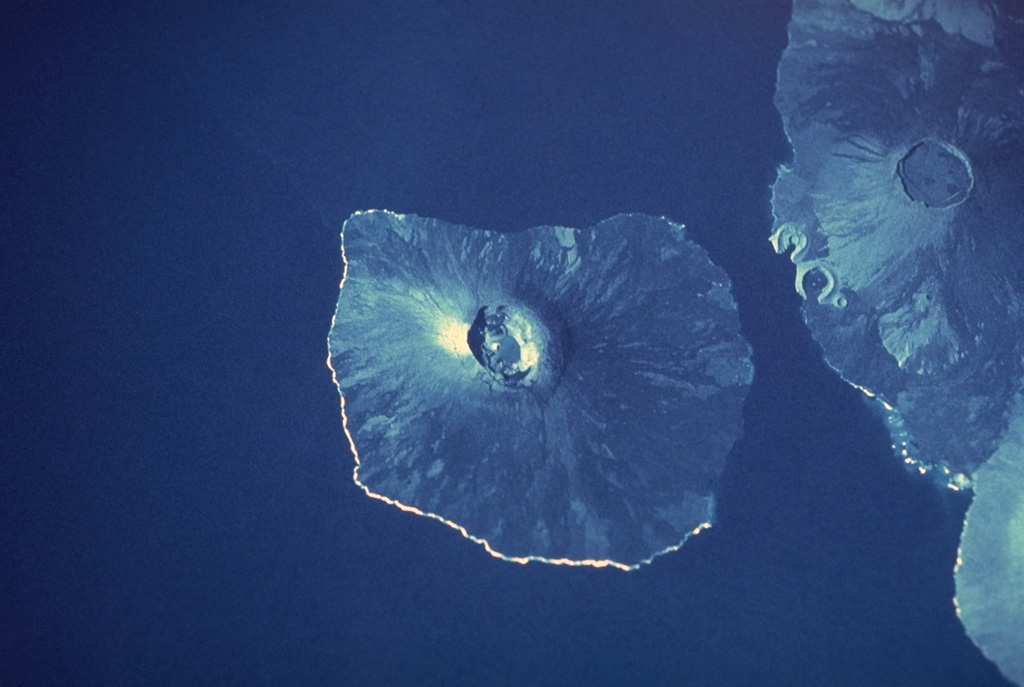 Two massive Galápagos shield volcanoes, their slopes darkened by young unvegetated lava flows that reach to the sea, appear in this space-shuttle photograph.  Fernandina volcano, the most active in the Galápagos Islands, forms a 30 x 34 km wide island with a 4 x 6.5 km wide caldera at its summit.  Darwin volcano, north of the midpoint of Isabela Island, has a 5-km-wide summit caldera.  The tuff cones of Tagus and Beagle are prominent along its western coast.  The light-colored area south of Darwin is the lower western flank of Alcedo volcano. NASA Space Shuttle image, 1989 (http://eol.jsc.nasa.gov/).