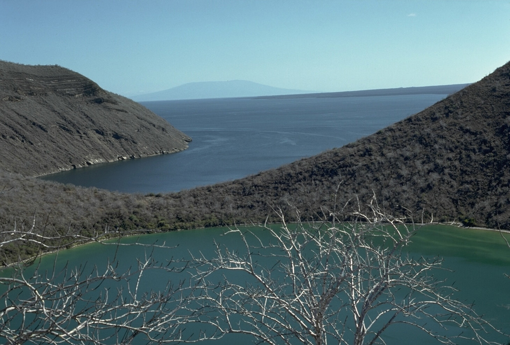 The smallest of at least four nested craters on Tagus tuff cone, located on the SW flank of Darwin volcano, is filled by a small lake.  The ridge at the upper left is the SE rim of the tuff cone, which is breached by Tagus Cove, one of the most renowned anchorages in the Galápagos archipelago.  Cerro Azul shield volcano rises in the distance at the southern end of Isabela Island.  Photo by Lee Siebert, 1978 (Smithsonian Institution).