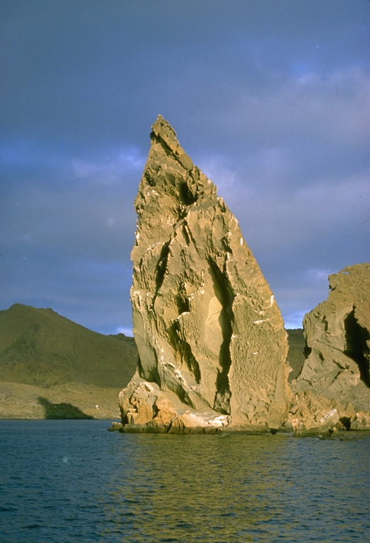 This prominent pinnacle is an eroded remnant of a tuff cone on Bartolomé Island, off the east coast of Santiago Island.  A wide variety of volcanic features flanks Sullivan Bay, one of the most visited boat anchorages in the Galápagos Islands.  These include tuff cones and cinder cones, a dissected solidifed lava lake, and vast fields of youthful pahoehoe lava flows. Photo by Lee Siebert, 1978 (Smithsonian Institution).
