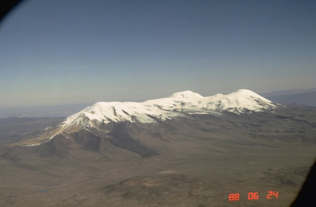 The elongated Coropuna volcanic massif is seen here from the NE.  The dark lava flow descending the NE flank at the left center is one of several youthful lava flows that overlie roughly 11,000-year-old glacial moraines.  The morphology of this flow and others on the SE and western flanks suggest that they are very young and postdate activity from the summit craters.   Photo by Norm Banks, 1988 (U.S. Geological Survey).