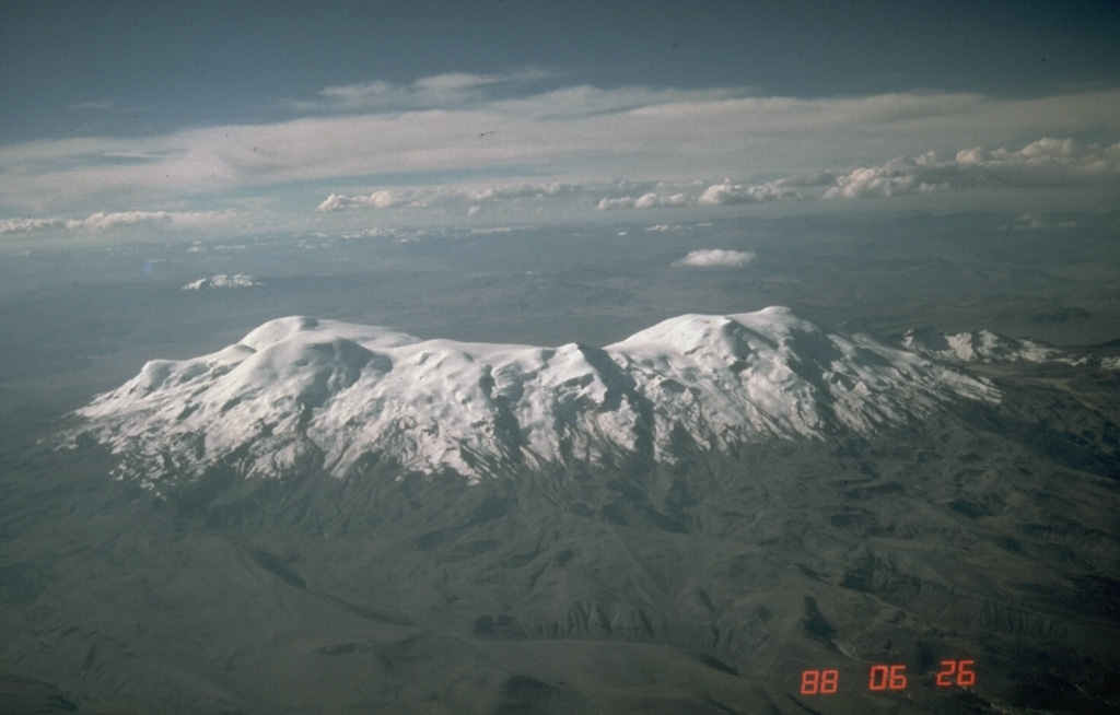 Nevado Coropuna, Perú's highest and largest volcano, is a massive ice-covered volcanic complex with at least a half dozen summit cones scattered over a 12 x 20 km area.  The 6377-m-high summit (left), seen here from the south, is located at the NW end of the complex.  Deep, steep-walled canyons surrounding the volcano give it an impressive topographic relief of more than 4000 m over a horizontal distance of 15 km.  Several young Holocene lava flows descend the NE, SE, and western flanks.   Photo by Norm Banks, 1988 (U.S. Geological Survey).