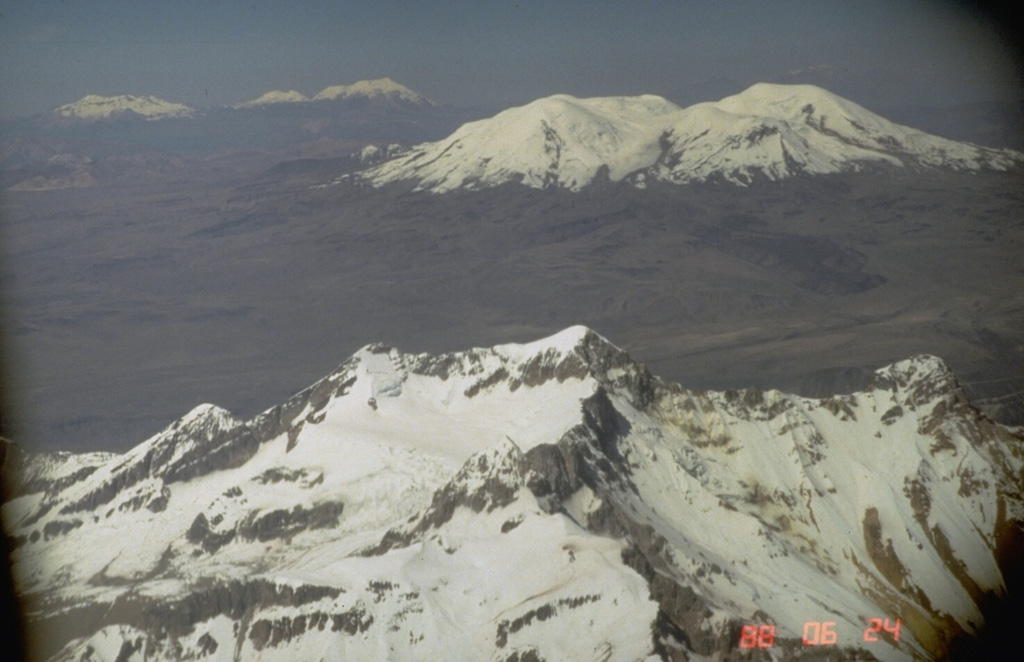 Volcanoes of three ages can be seen in this aerial view across northern Perú.  The eroded, 6093-m-high Solimana volcano (foreground) has not erupted since the Pleistocene, but has an active fumarole.  It is located NW of the younger Coropuna volcano (upper right), which has produced major flank lava flows during the Holocene.  The three-peaked Sabancaya volcanic complex (upper left) includes the historically active cone of Sabancaya proper, which is flanked on the left by Hualca Hualca volcano and on the right by Ampato volcano. Photo by Norm Banks, 1988 (U.S. Geological Survey).