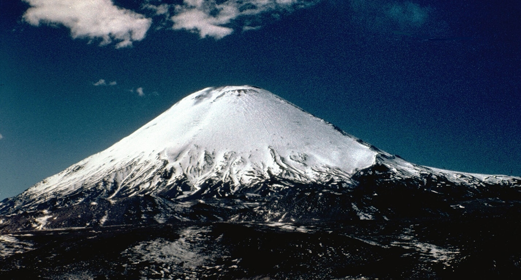 Symmetrical Volcán Parinacota rises north of Lake Chungará in the foreground.  The lake was formed when collapse of an ancestral Parinacota edifice about 8000 years ago produced a massive 5-6 cu km debris avalanche that dammed a preexisting river.  Subsequent eruptions of andesitic aa lava flows and andesitic pumice and scoria flows constructed the modern conical edifice, obscuring the avalanche source scarp.  The summit of Parinacota volcano contains a pristine, 300-m-wide crater. Photo by John Davidson, University of Michigan (courtesy of Hugo Moreno, University of Chile).