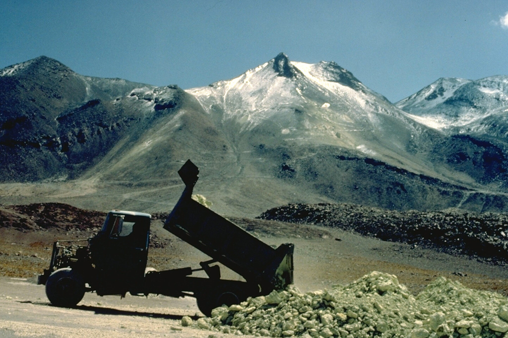 An ore truck dumps a load of sulfur ore at Aucanquilcha volcano in northern Chile.  The world's highest mine is located near the summit of 6176-m-high Volcán Aucanquilcha.  A switchbacked road leads to the sulfur mines, which are located in areas of extensive hydrothermal alteration along the elongated summit ridge of the volcano.  Copyrighted photo by Katia and Maurice Krafft, 1983.