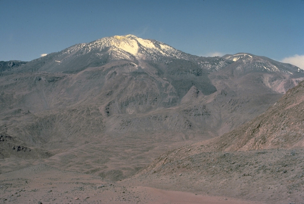 Volcán Putana, seen here from the NW, is part of large, roughly N-S-trending volcanic complex that was formed almost exclusively by lava effusion.  Vigorous fumarolic activity is visible for many km from the summit of Putana volcano and sulfur is mined in the summit region.  The main edifice consists of accumulated postglacial lava flows mantling an older pre-Holocene volcano.  The youngest lava flows are viscous and rarely extend more than 3 km.  Little is known of the eruptive history of this volcano.  Copyrighted photo by Katia and Maurice Krafft, 1983.