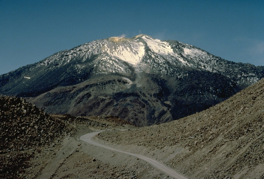 A road leads to a sulfur mine near the summit of 5890-m-high Putana volcano.  Active fumaroles can be seen above several vents in the hydrothermally altered summit region.  The main edifice was constructed primarily by lava effusion, with late-stage eruptions producing an accumulated pile of short, thick lava flows.  Flank vents have also emitted fresh-looking lava flows. Copyrighted photo by Katia and Maurice Krafft, 1983.