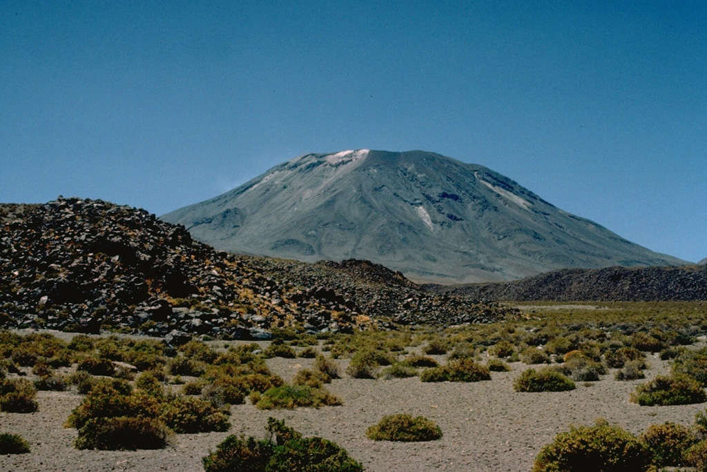 The blocky lava flow in the foreground is one of several young flows on the NW flank of Láscar volcano.  The most prominent flow traveled down the north flank and extended 6 km to the NW.  Láscar, northern Chile's most active volcano, has produced frequent explosive eruptions since its first recorded historical eruption in the mid-19th century.  Recent eruptions have included lava dome growth in the summit crater. Copyrighted photo by Katia and Maurice Krafft, 1983.