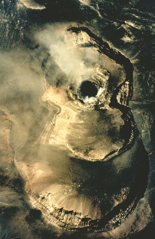 A vertical aerial photograph shows a growing lava dome in the summit of Láscar volcano on March 20, 1992.  Three of six summit craters located along an E-W trend are seen in this photo, with north to the top.  The lava dome (the dark steaming mass at left center) was first seen on March 4, but may have formed earlier following phreatic explosive eruptions in October 1991.  Eruption plumes were visible beginning in late March.  Ashfall occurred on May 15 and night glow visible May 21-23 marked the last reported activity of the 1991-92 eruption. Photo by Moyra Gardeweg, 1992 (Servicio Nacional de Geología y Minería, Chile).