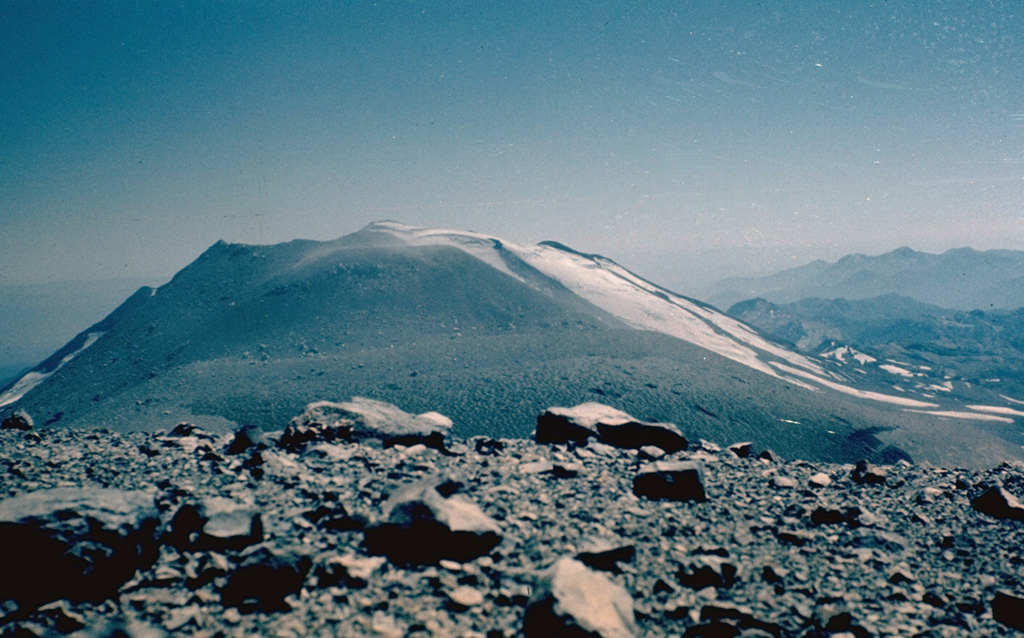 Volcán Nuevo, the newest cone of the three-peaked Nevados de Chillán volcano, was formed beginning in 1861.  It grew between Cerro Blanco and Volcán Viejo, which anchor the NW and SE ends of the complex, respectively.  Volcán Nuevo has been the most active volcano of the complex since its birth.  In 1973, the year of this photo, a long-term eruption began on the SE flank of Volcán Nuevo, producing a cone that by 1987 had grown above Volcán Nuevo.  Nevados de Chillán is one of the most active volcanoes of the Central Andes of Chile.   Photo by Hugo Moreno, 1973 (University of Chile).