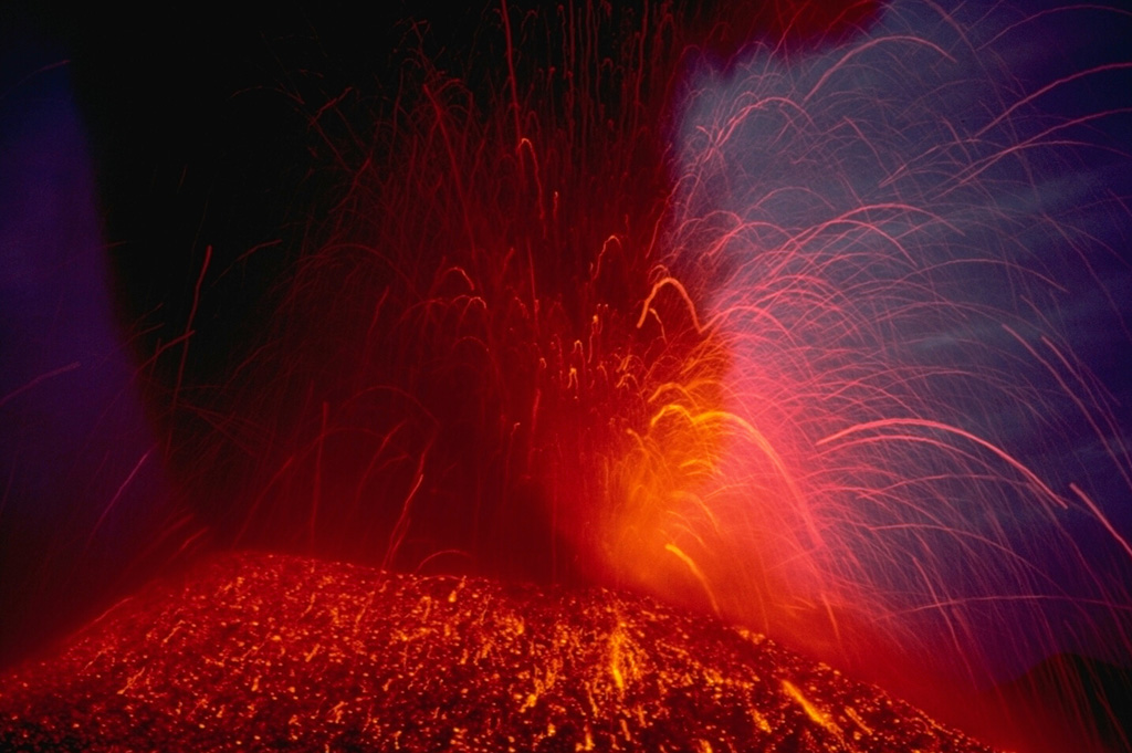 Strombolian eruptions eject incandescent fragments above a cinder cone on the NE flank of Lonquimay volcano in the central Chilean Andes in January 1989.  The parabolic arcs of individual volcanic bombs can be seen at the right in this time-exposure photograph.  The flanks of the cone are colored by still-cooling ejected blocks.  The cinder cone, which began forming on Christmas day 1988, was named Navidad. Copyrighted photo by Katia and Maurice Krafft, 1989.