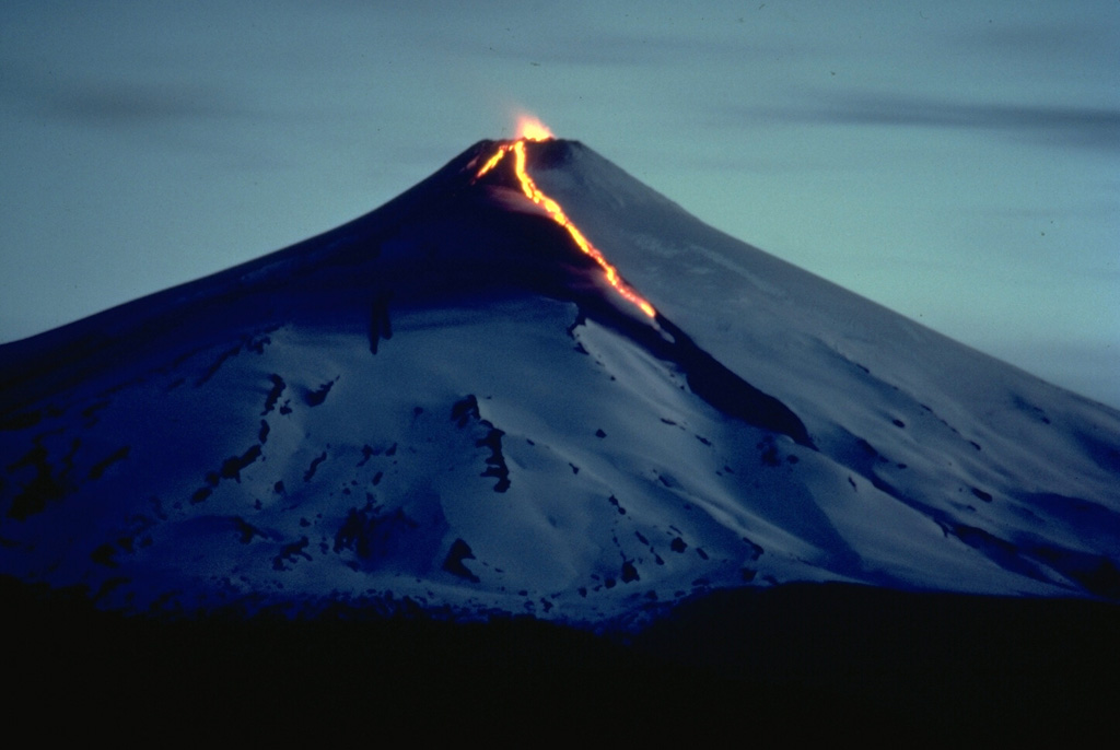A night-time view of Chile's Villarrica volcano in December 1984 shows an incandescent lava flow descending the north and NE flanks and strombolian eruptions from the summit crater.  The 1984-85 eruption began with small explosions and tephra emission on August 11.  Renewed explosions, accompanied by lava flows, began on October 30, and lasted until February 26.  Beginning in April and continuing until November 18, lava fountains and weak explosions producing minor ash were observed from Pucón, a town at the north foot of the volcano.  Copyrighted photo by André Demaison, 1984 (courtesy of Katia and Maurice Krafft).